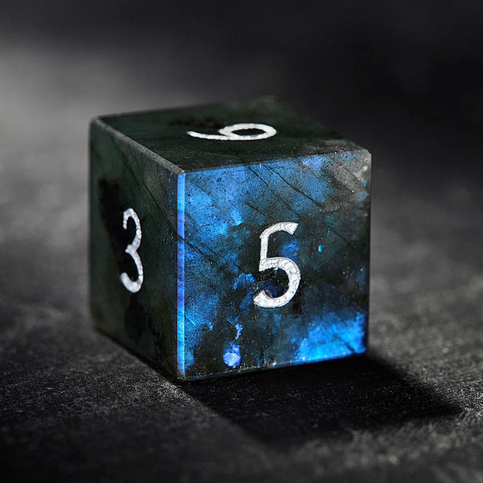 a blue and black dice with the number five on it