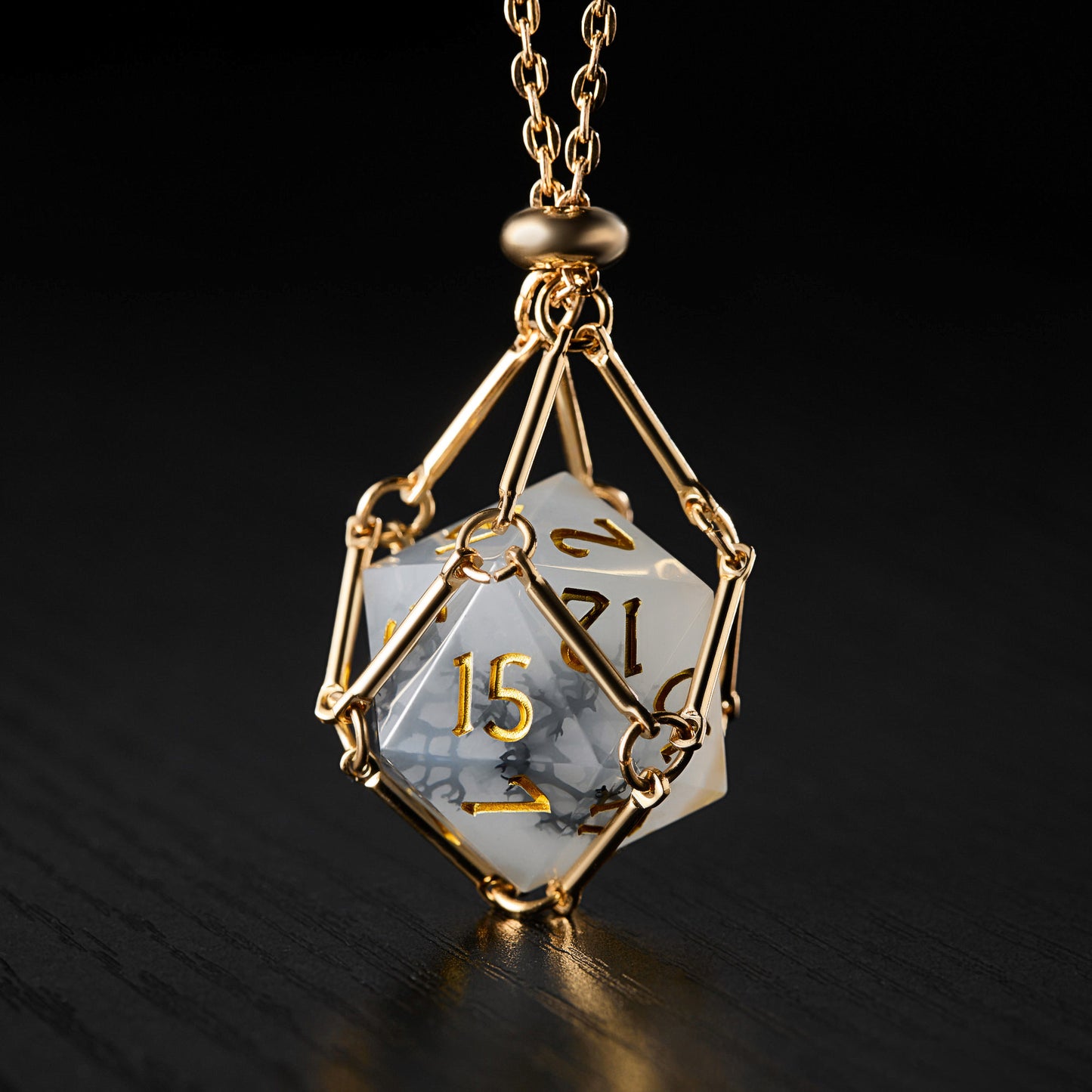 a golden necklace with a white cube on a black background
