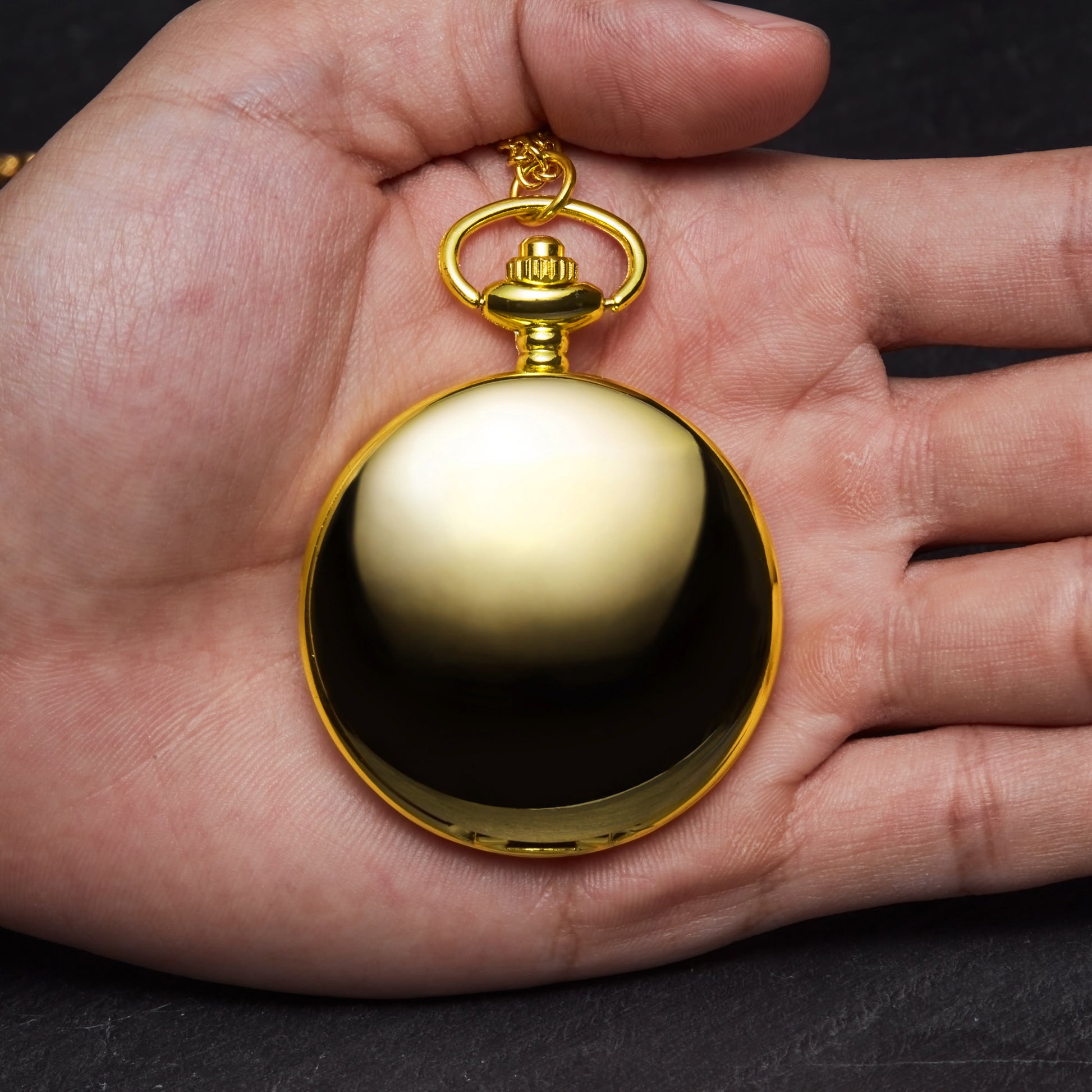 a hand holding a gold colored pocket watch