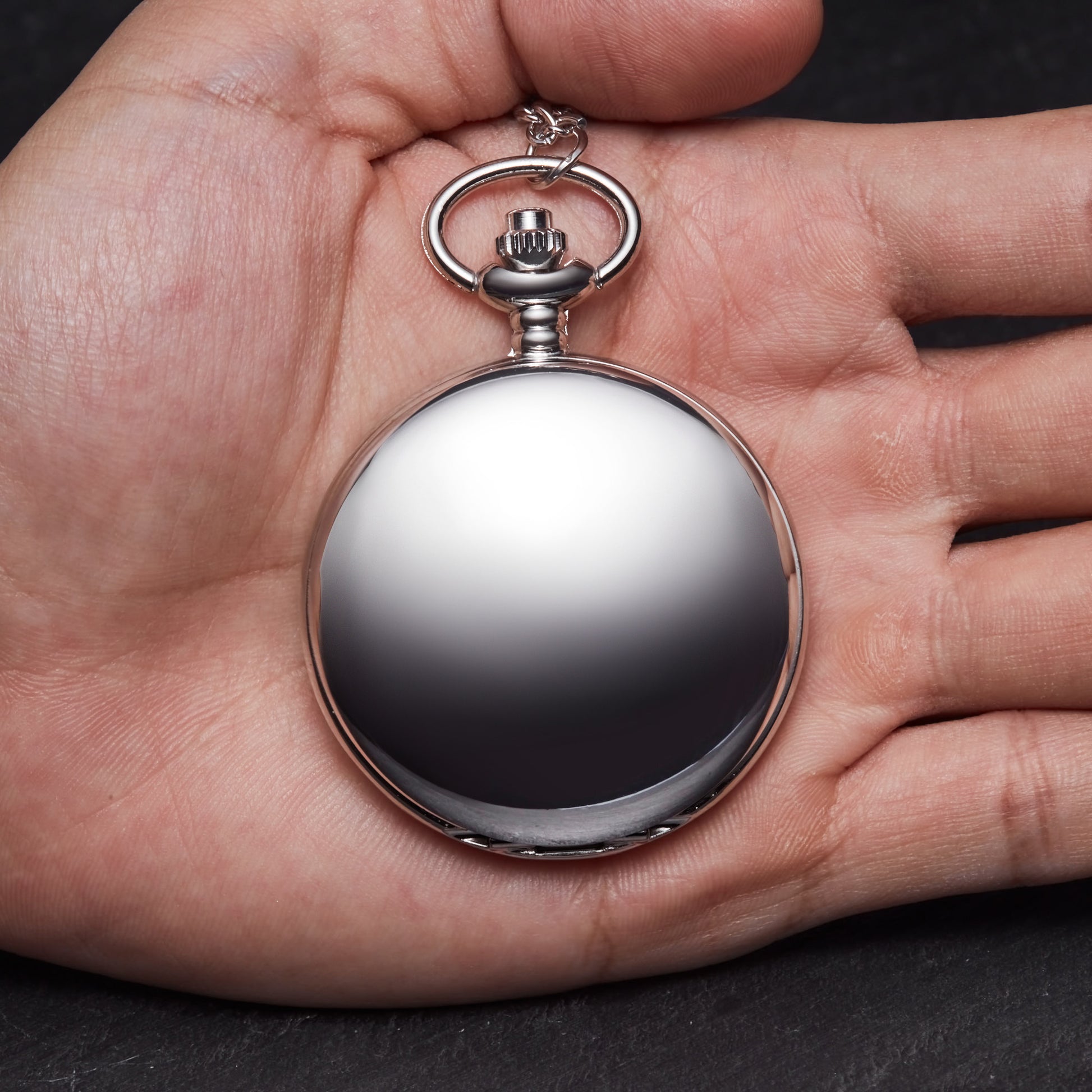 a person holding a silver pocket watch in their hand